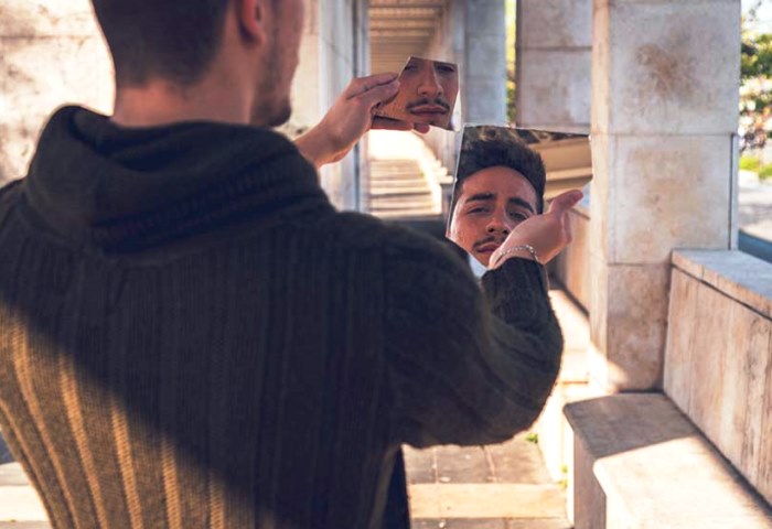 Young  man looking at himself in a broken mirror